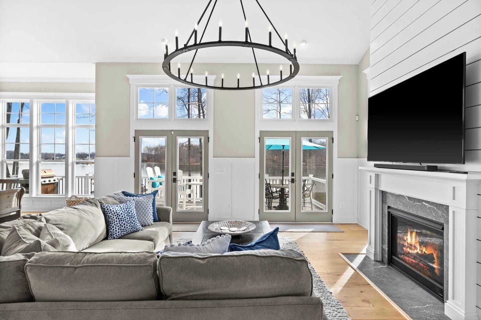 Great Room - A large sectional and statement chandelier anchor the space, with French doors pulling every eye toward the water.