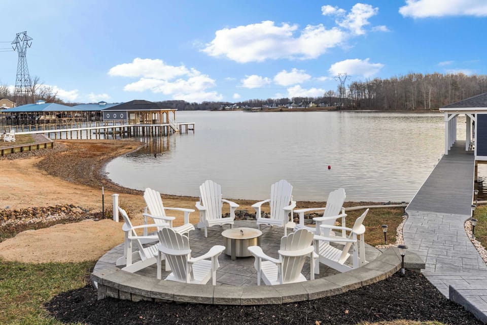Fire Pit - White Adirondack chairs arranged around the fire pit, with the boathouse and lake as the backdrop.