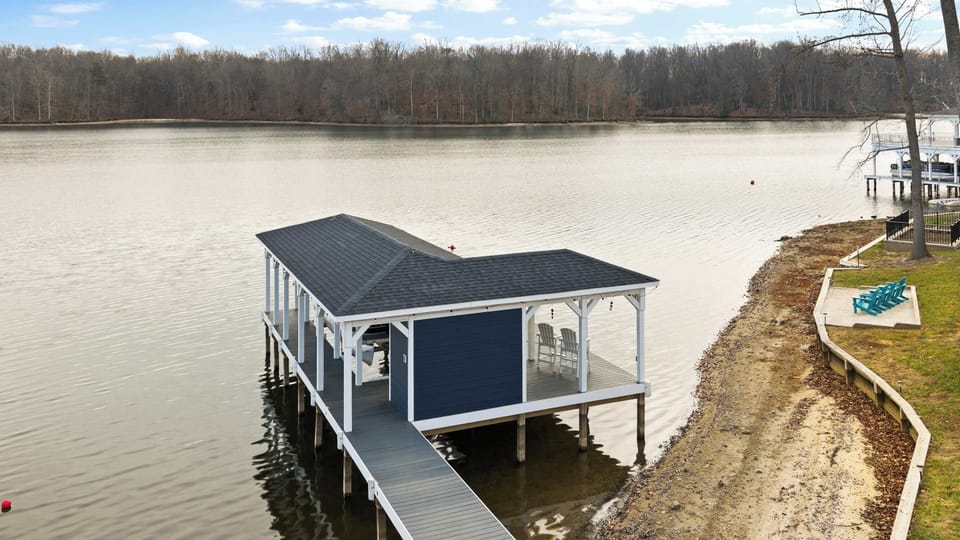 Exterior - The boathouse dock from water level on a bright day, the boat lift visible inside the covered slip.