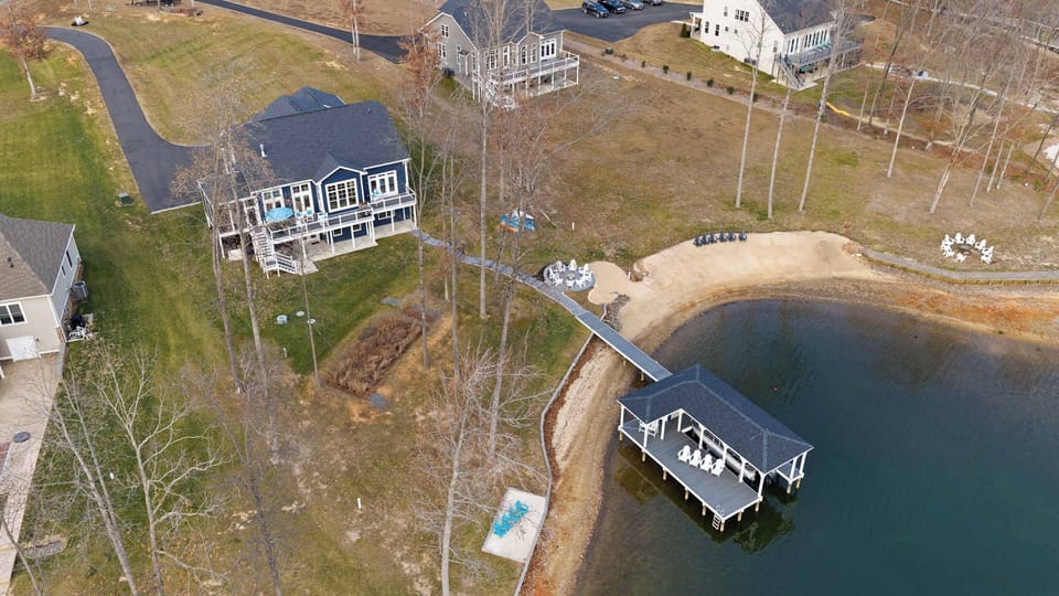 Exterior - Aerial from above and behind the property captures the house, dock, and fire pit in one composition.