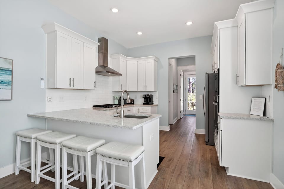 Airy, coastal‑blue kitchen with crisp white cabinetry and a sunlit peninsula perfect for casual gatherings.