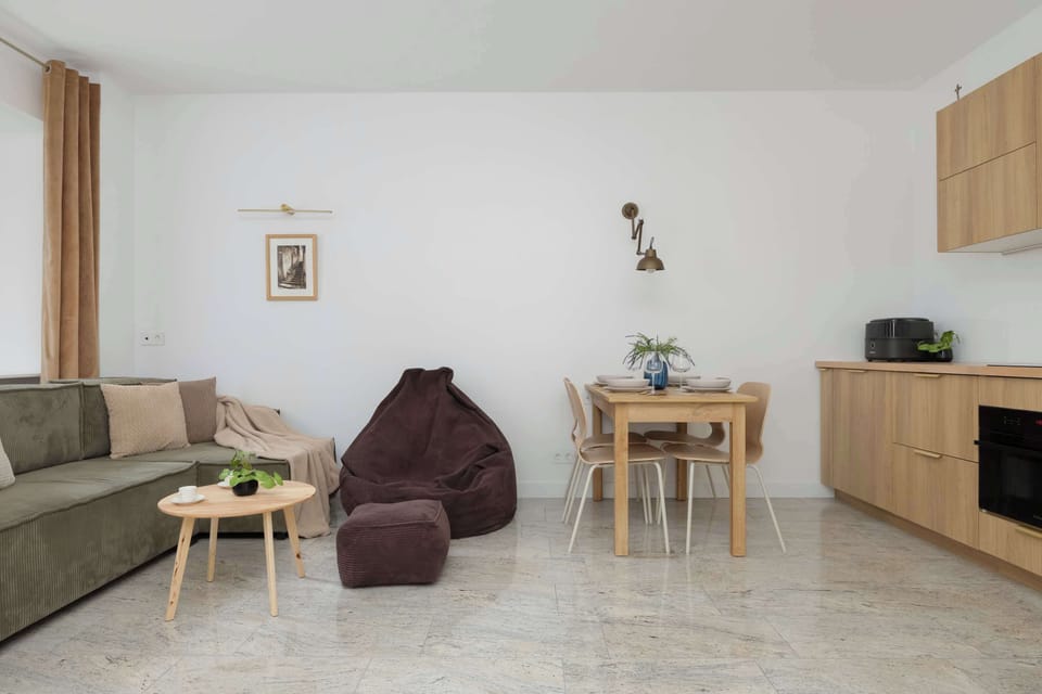 A view of the living room and dining area highlighting the open layout and the cohesive color scheme of the furniture. The floor features light marble-patterned tiles that add a touch of elegance.
