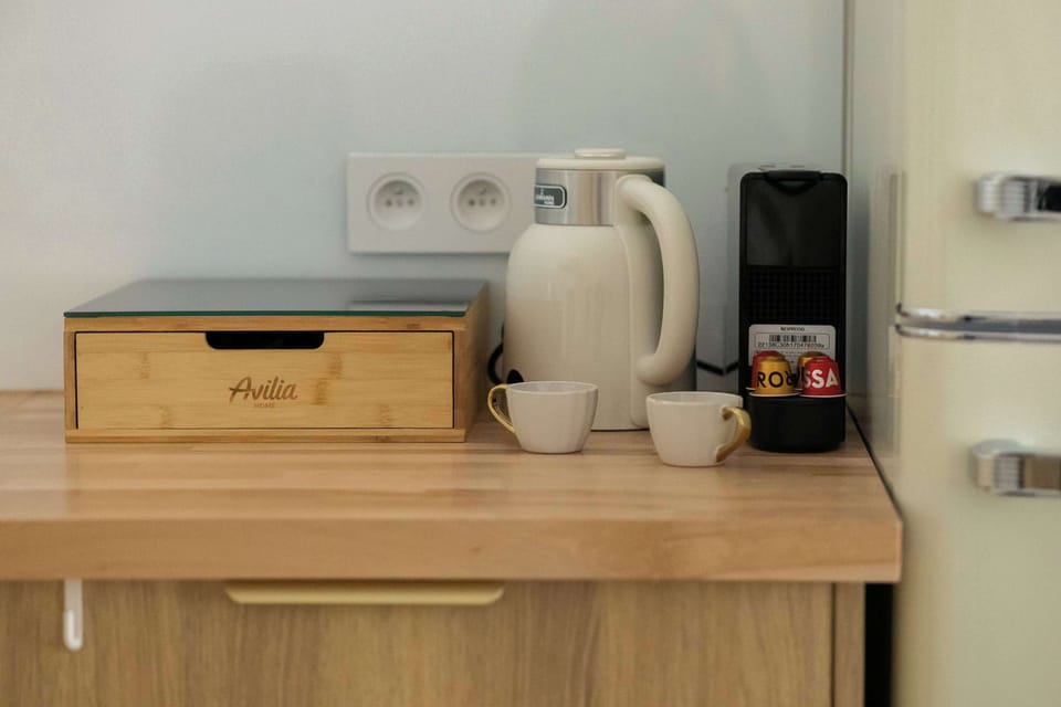 A close-up of a section of the countertop featuring a coffee-making set, a wooden bread bin, and a stylish retro refrigerator. These details demonstrate a commitment to guest comfort and the aesthetics of the furnishings.