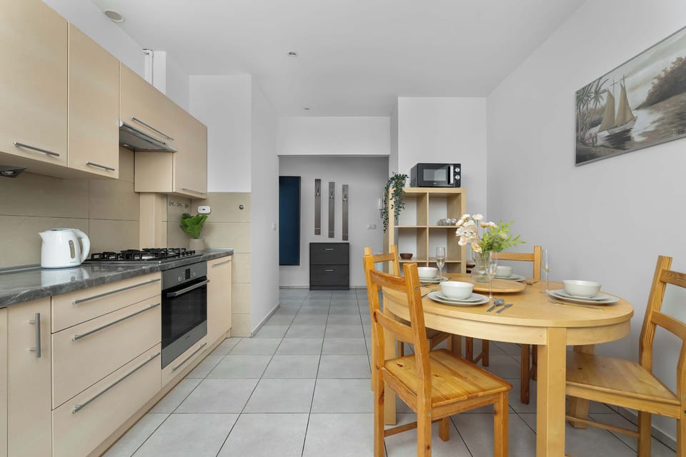 A separate kitchen area with bright cabinets, a wooden dining table for four, and essential appliances like an oven and stovetop. The layout is functional and clean, perfect for preparing home-cooked meals.