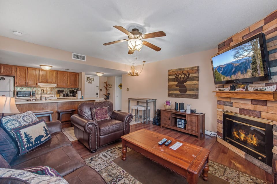Unwind in your cozy living space featuring rustic wood accents, a crackling fireplace, and comfy leather seating perfect for mountain evenings.