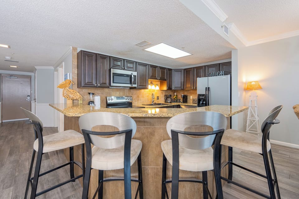 Warm under-cabinet lamps invite you to gather around the breakfast bar in the kitchen area