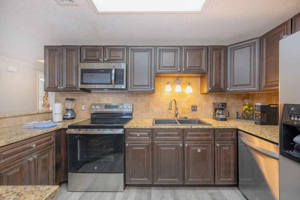 Dark wood cabinetry surrounds the kitchen sink where you prepare fresh meals to enjoy with your family
