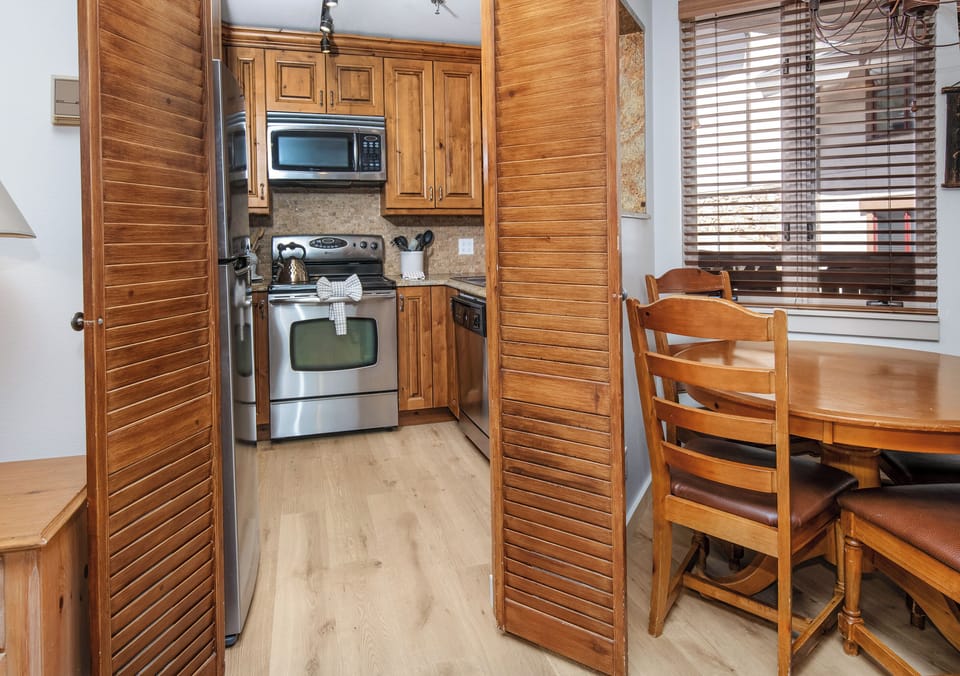 Step into your well-equipped kitchen featuring warm wood cabinetry, modern stainless steel appliances, and a cozy dining nook bathed in natural light—your perfect spot for morning coffee or meal prep.