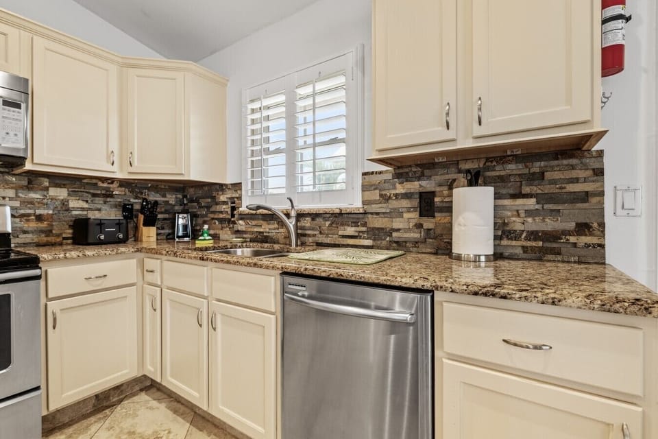 🧼 Clean-up is effortless thanks to the stainless steel dishwasher, featuring bright plantation shutters that let in beautiful natural light.