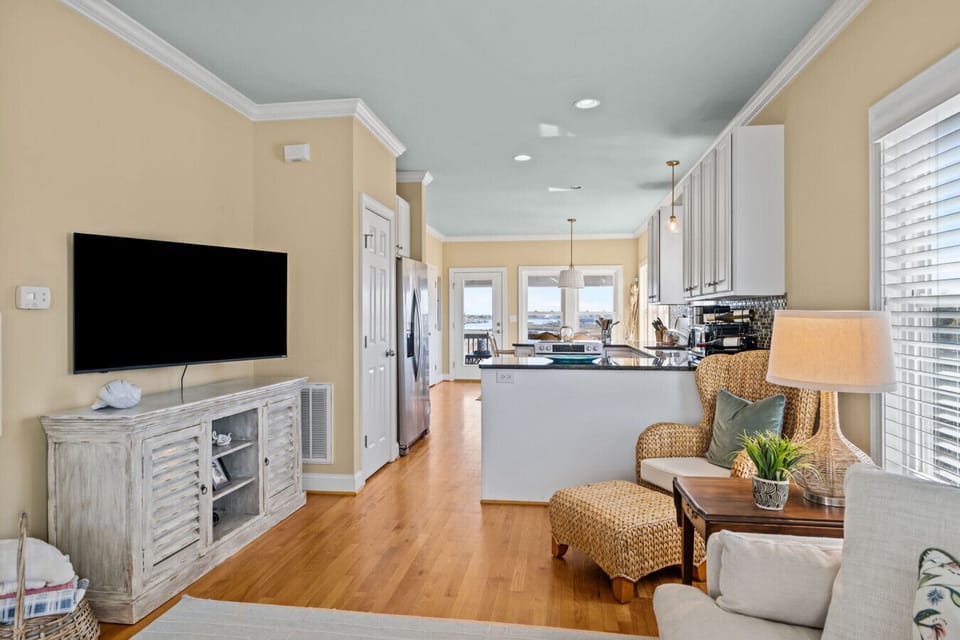 Coastal-style open living area with kitchen, seating, and TV in Marsh House, Atlantic Beach