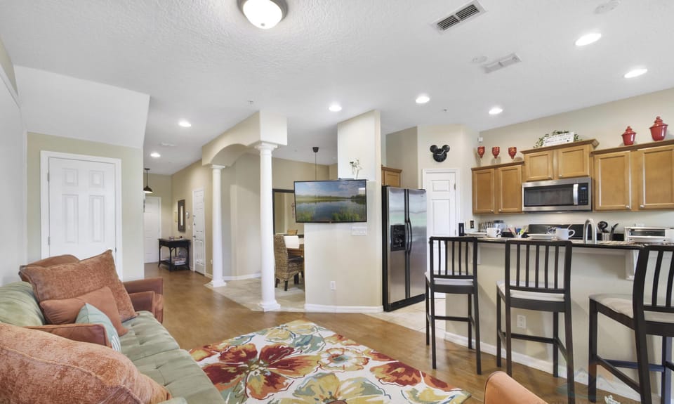 Open-plan living area with a cozy sofa and modern kitchen, perfect for relaxing and entertaining.