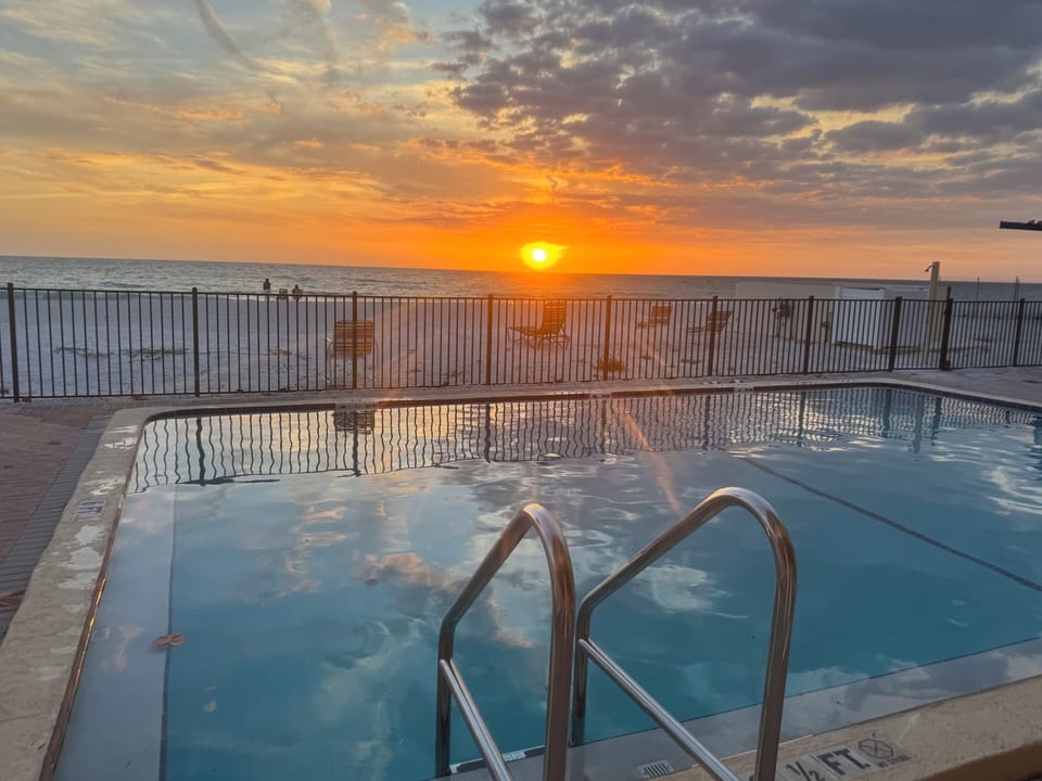 Condo pool with tables and chairs and large shaded seating area! 