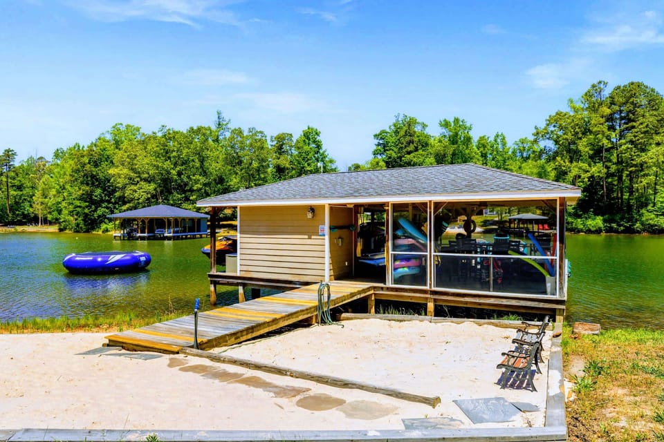 Lakefront - From the sandy beach, a boardwalk leads to the screened boathouse, with the water trampoline bobbing just offshore.