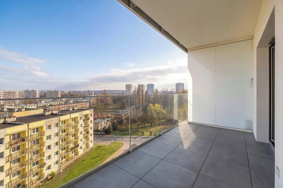 A spacious balcony with a wide view of the surrounding city and residential buildings. The open layout provides plenty of room to relax and enjoy the skyline.
