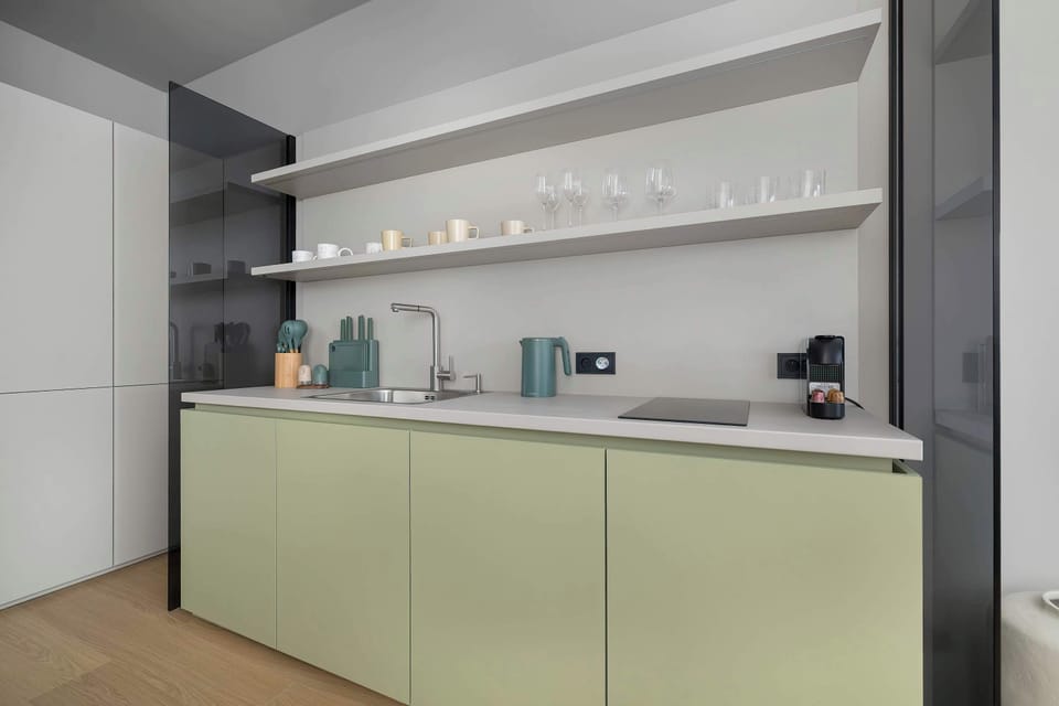 A close-up view of the kitchenette highlighting the cabinetry and countertop space. Subtle lighting and neutral finishes enhance the modern aesthetic.