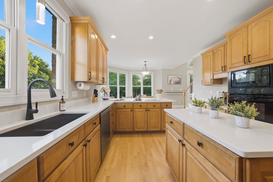 Bright modern kitchen with warm wood cabinetry and sleek stainless‑steel appliances.