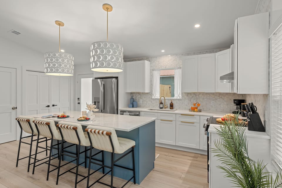 Bright modern kitchen with a blue island, warm gold accents, and inviting breakfast‑ready styling.