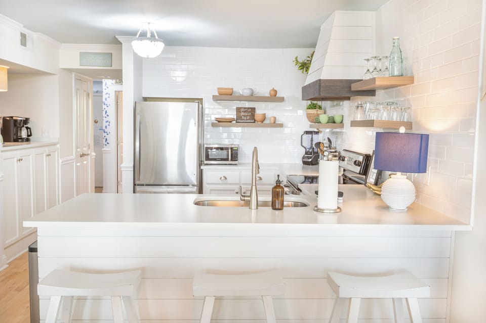 Bright coastal kitchen with white cabinetry, warm wood accents, and a clean, inviting island for gathering.