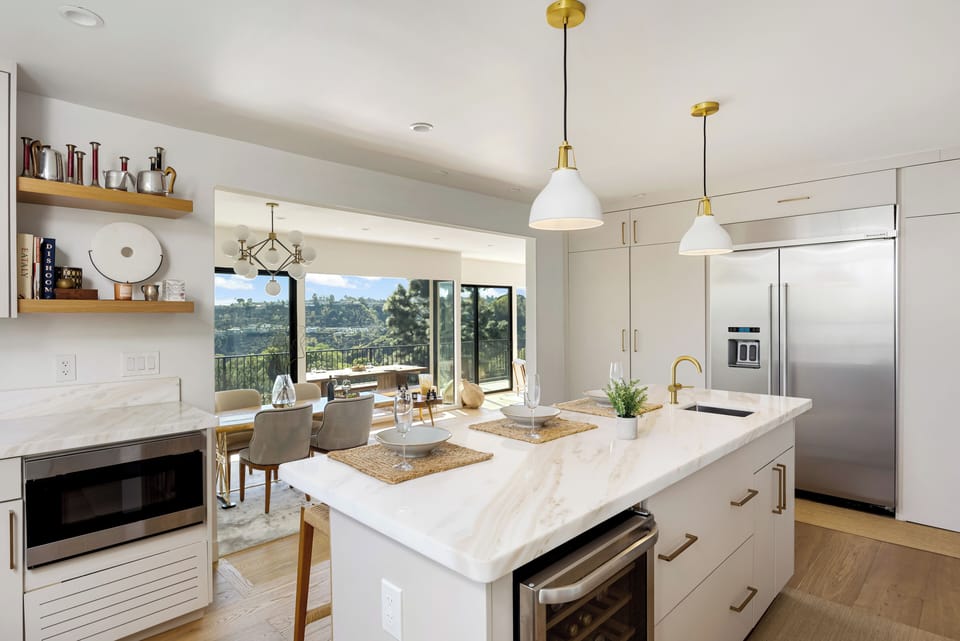Fully equipped chef’s kitchen featuring high-end stainless steel appliances, a large marble island, and breakfast bar seating.