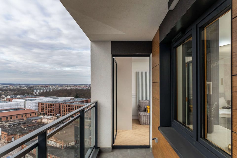A shot from the corner of the balcony showing its spaciousness and the quality of the building’s facade finish. Through the open balcony doors, you can see the warm, inviting interior of the Apartment.