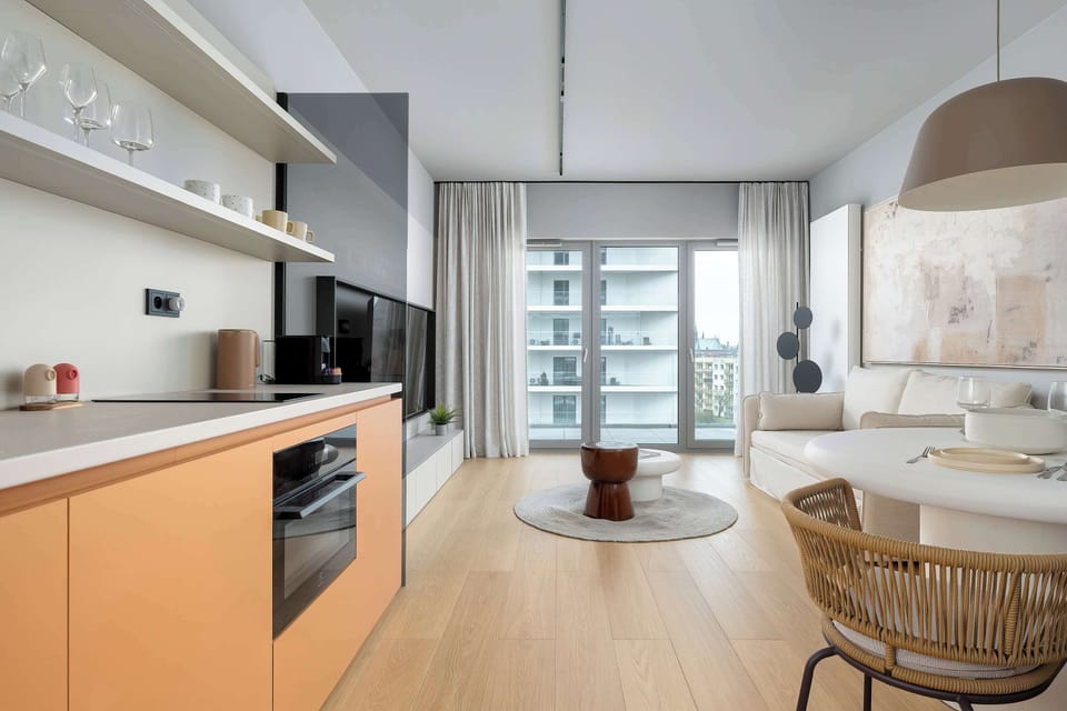 A modern kitchenette with sleek cabinetry and a light wooden countertop blends seamlessly into the living space. The layout is compact yet functional, with clean lines and integrated appliances.