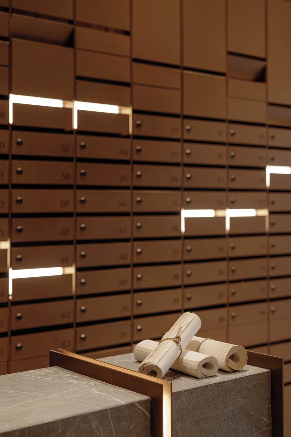 A detailed close-up view of a slatted wooden feature wall outfitted with floating illuminated shelves. Clean, rolled white towels rest neatly on a low bench below the wooden structure.