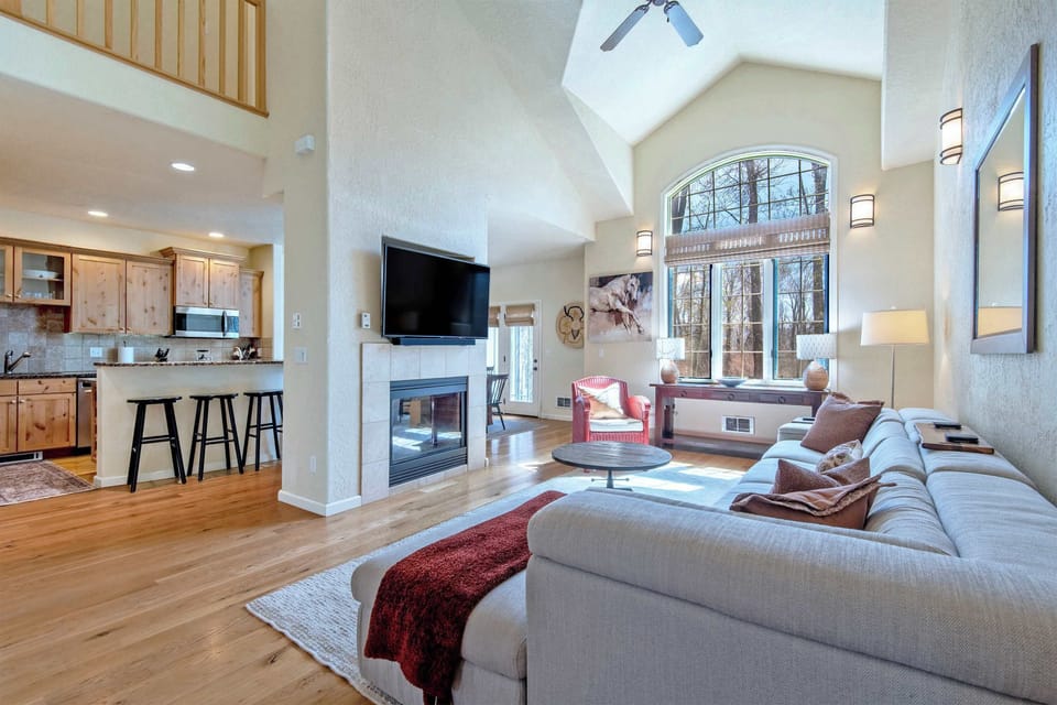 Grand open living space with fireplace, vaulted ceilings, and designer comfort