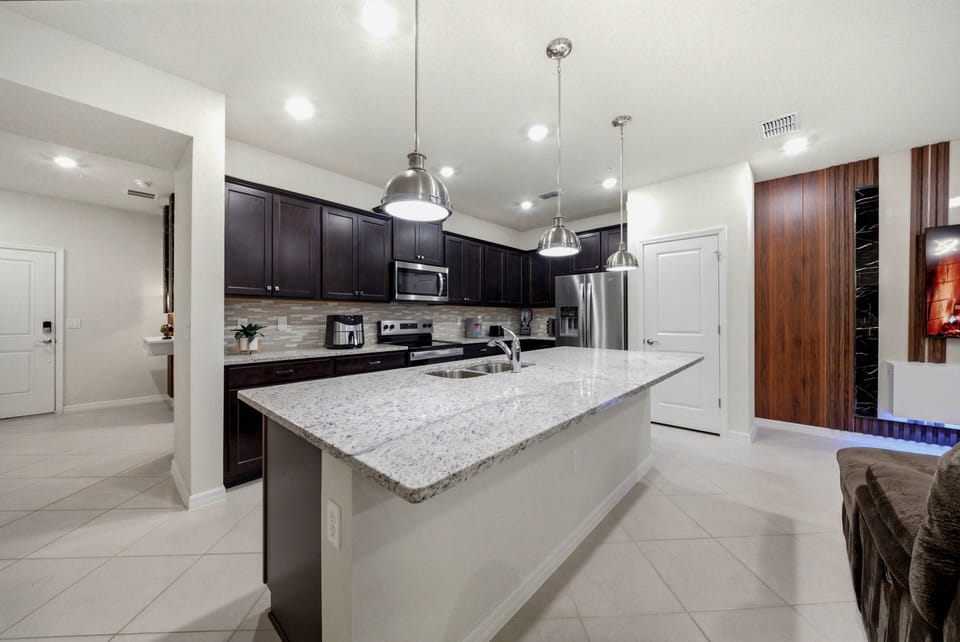 Welcome to a beautifully designed kitchen with rich dark cabinetry and a stunning granite island, ideal for casual dining. The polished tile flooring and sleek stainless steel appliances create a warm, inviting space for meal.