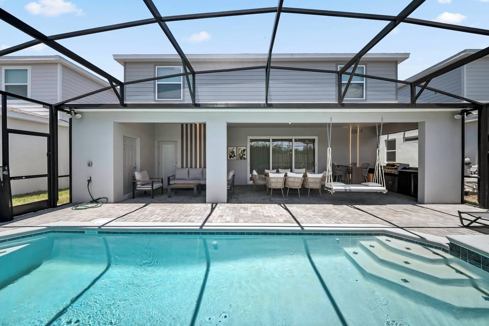 Experience a sunlit oasis featuring a sparkling pool within a stylish screened enclosure, perfect for relaxation. Enjoy seamless access from the pool to the dining area, creating an inviting space for delightful al fresco meals.