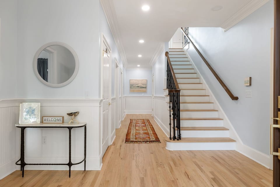 Step into your elegant entryway with gleaming hardwood floors and a graceful staircase leading to your private upper level.