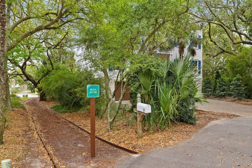 Beach access sign marks the pathway to waterfront relaxation in this lush, tropical neighborhood setting.
