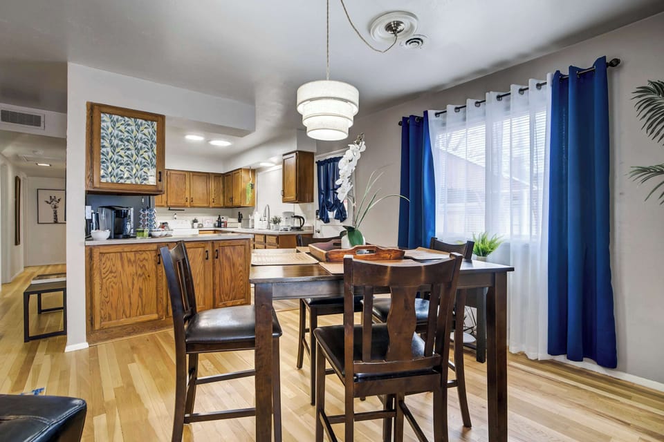 A wider angle captures the dining room's position between the living area and kitchen, highlighting the home's open, single-level flow. The tiered pendant overhead adds a decorative focal point above the table without overwhelming the space.