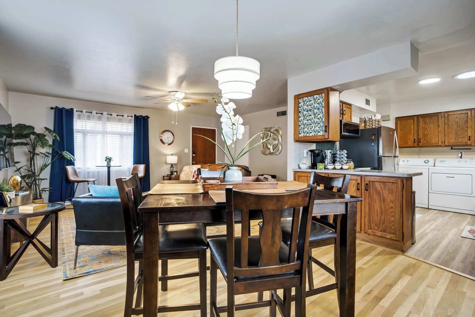 The dining table comfortably seats the group, with the kitchen's warm oak cabinetry visible just beyond. Wall art and potted greenery add warmth and color, keeping the transition between dining and kitchen feeling natural and cohesive.
