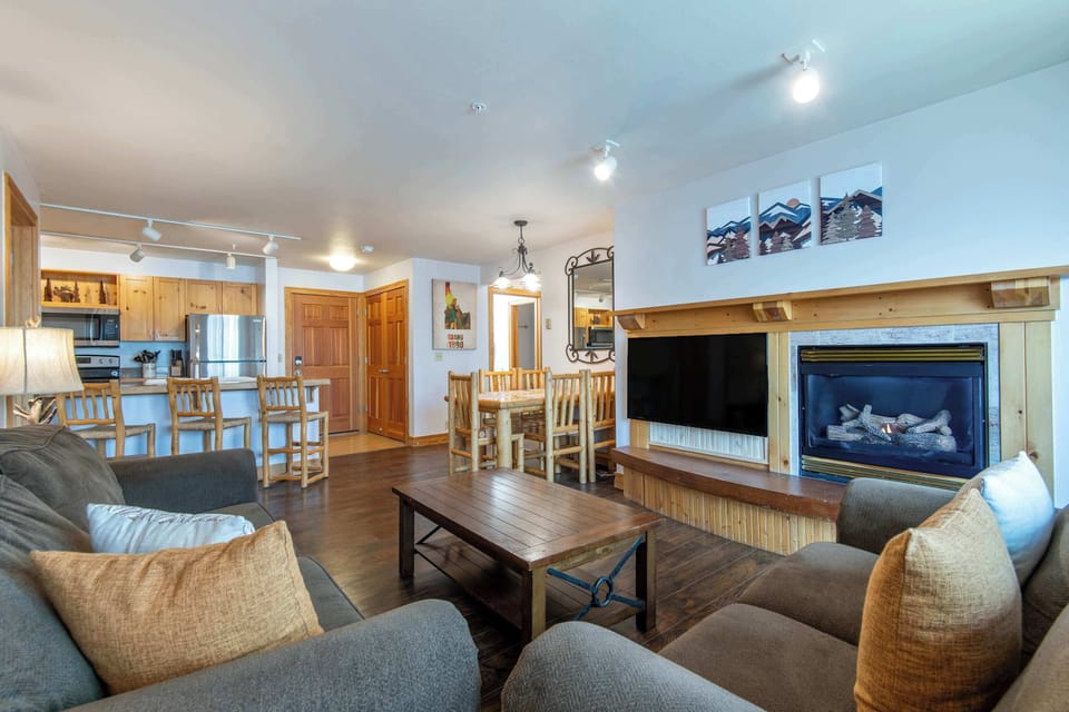 Warm, open-concept living with a fireplace, dining space, and breakfast bar