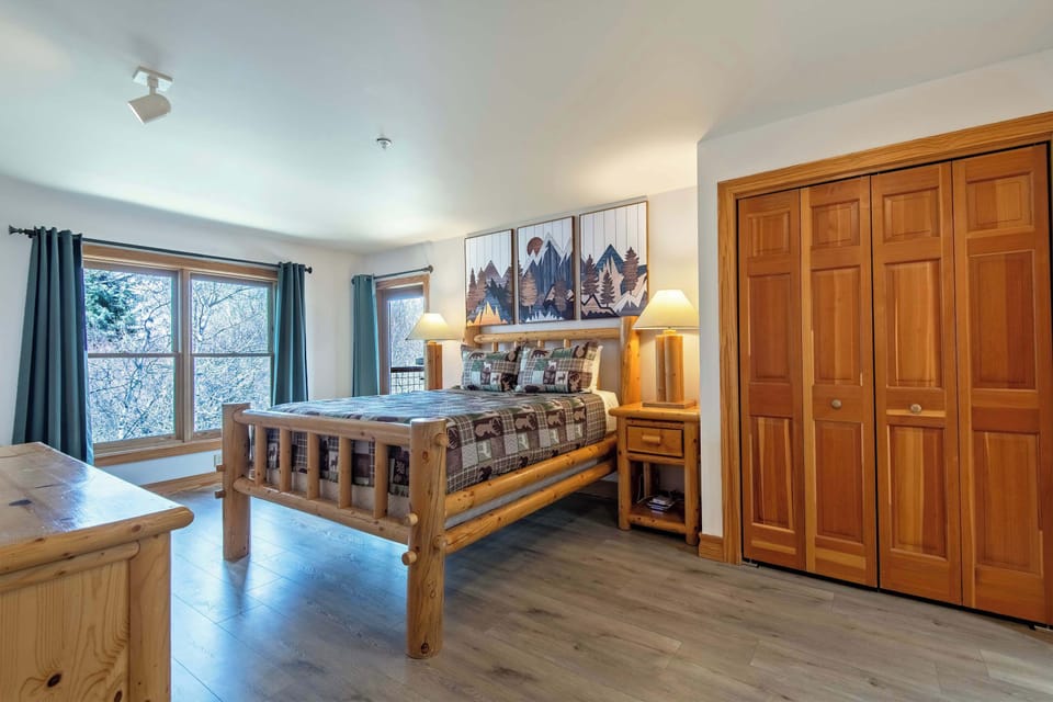 Spacious primary bedroom with a queen bed, TV, and warm mountain lodge style