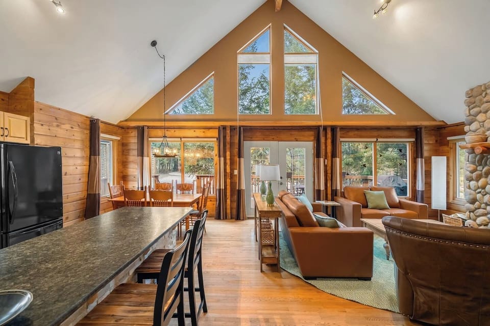 Main floor living room with a wood-burning fireplace, board games, cozy seating options and walkout access to the deck.