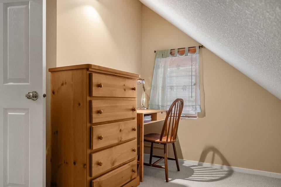 Third bedroom, located upstairs, with a queen bed, dresser, dedicated workstation and room-darkening shades.