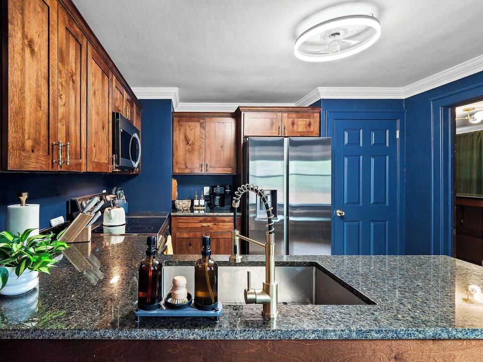 Kitchen w/ bold blue cabinetry, granite counters & plenty of prep space.
