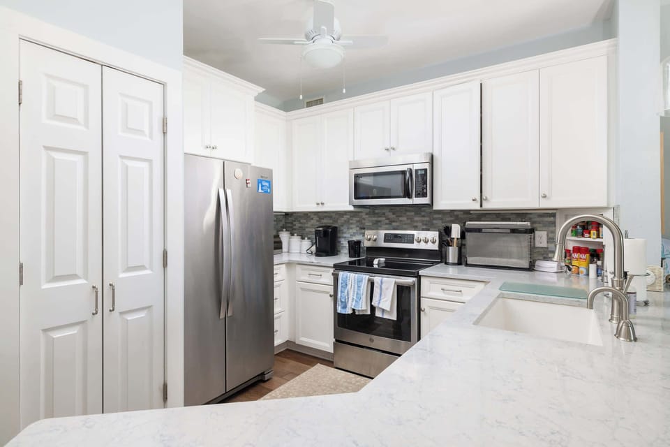 Fully equipped kitchen with refrigerator, stove, oven, microwave, dishwasher, coffee maker and essentials for cooking and meal prep