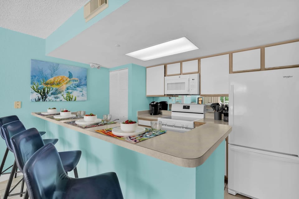 Fully equipped kitchen with breakfast bar seating, perfect for quick bites and morning coffee.