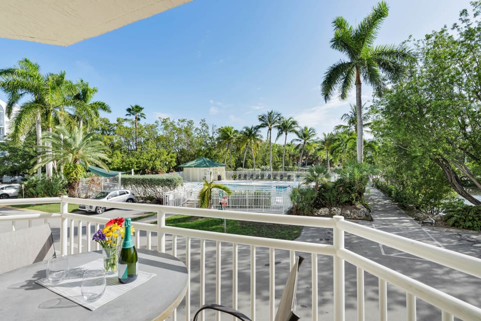 Private balcony overlooking the pool, palms, and tropical walking paths.