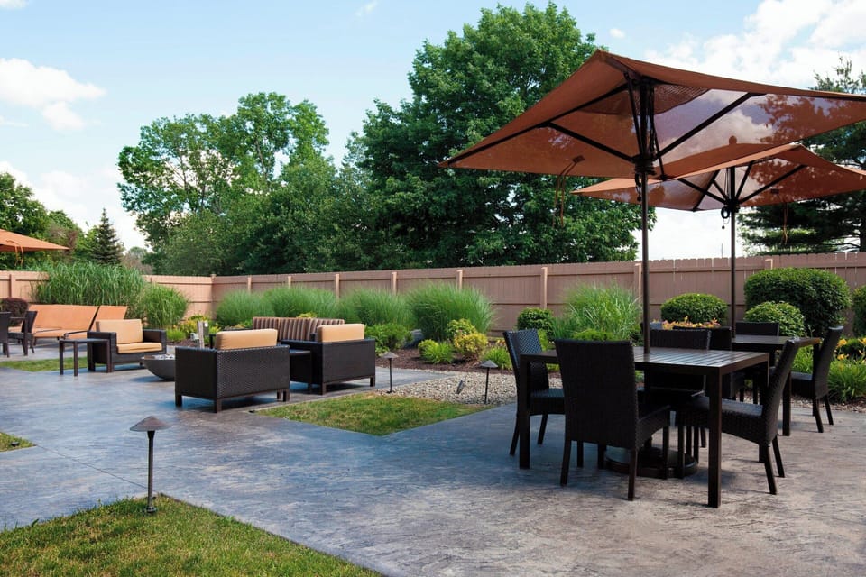 Gather for sunny patio meals under umbrellas in landscaped serenity.