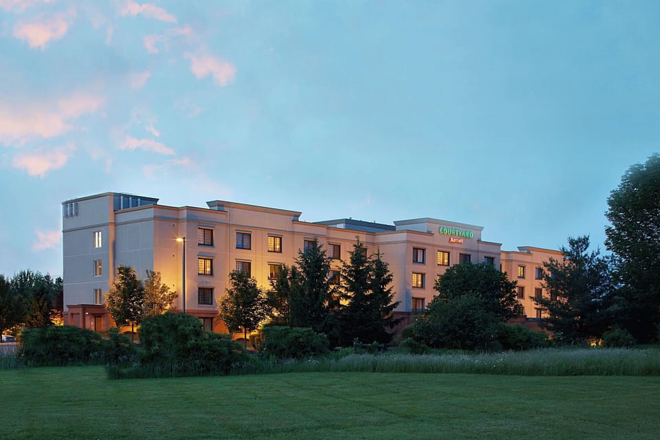 Arrive to a welcoming, well-lit hotel exterior at twilight.