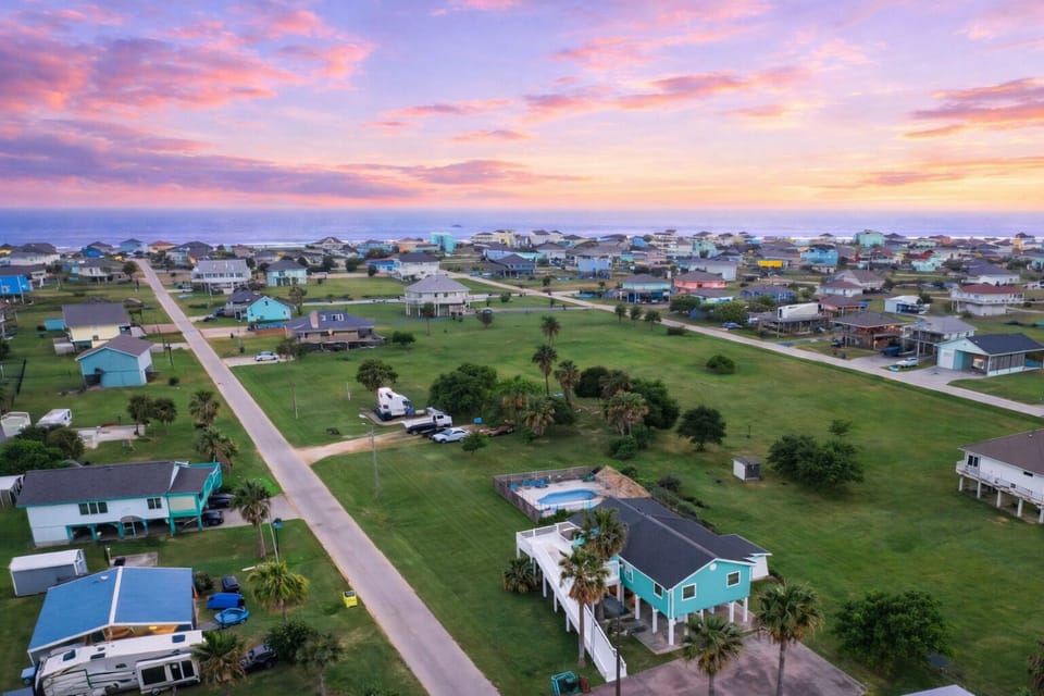 Aerial neighborhood view showing the walkable beach, coastal community layout and nearby homes.