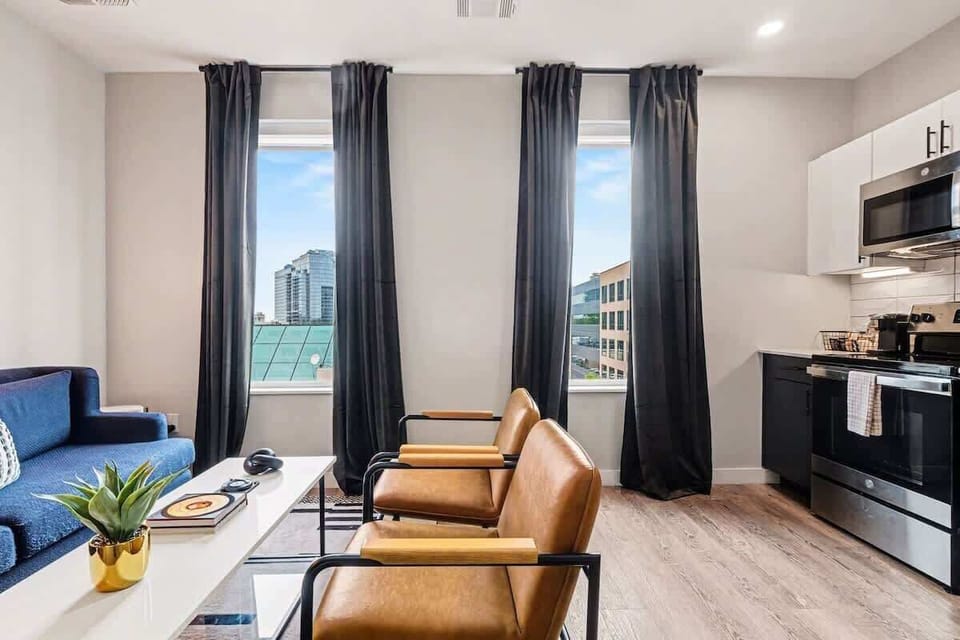 Bright and open living area featuring a smart TV and plush furnishings. Connects to the dining area and kitchen.