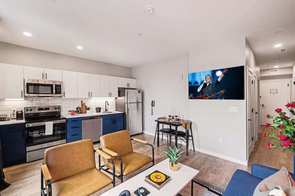 Bright and open living area featuring a smart TV and plush furnishings. Connects to the dining area and kitchen.