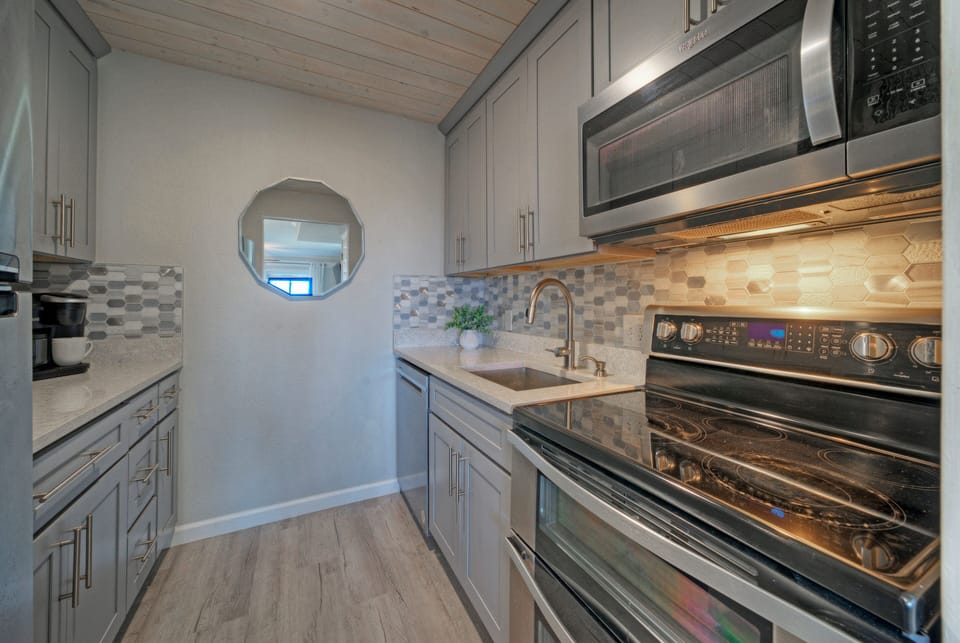 Modern kitchen equipped with white cabinetry and stainless steel appliances.