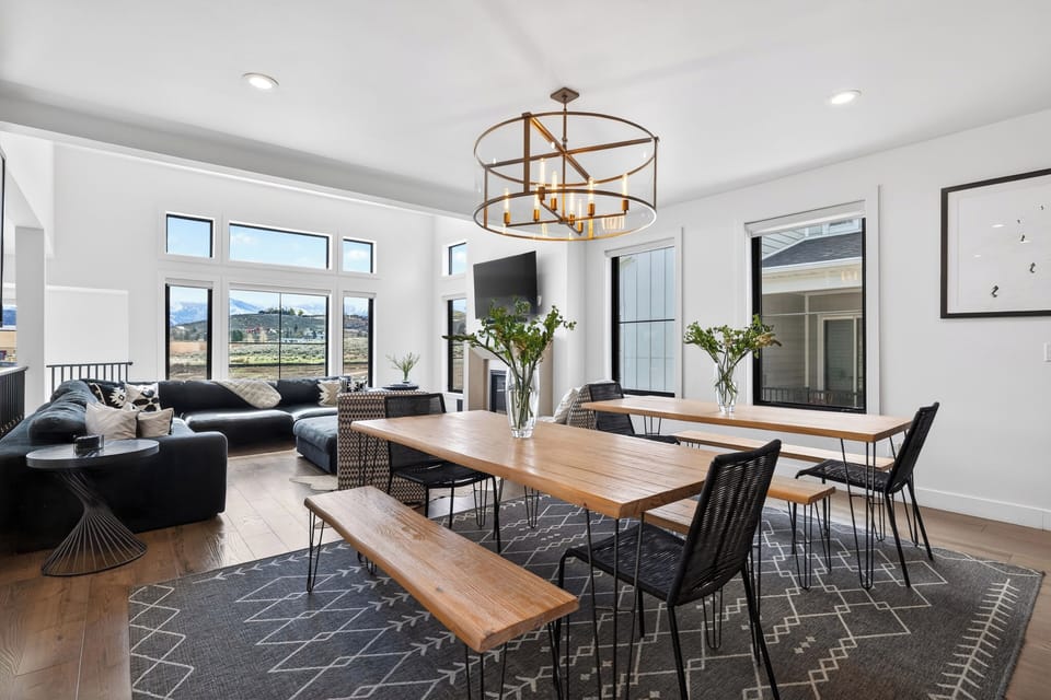 Open‑concept dining area with warm wood accents, modern lighting, and mountain views through oversized windows.