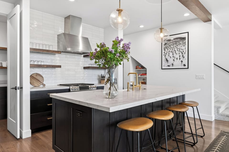 Bright modern kitchen with a marble island, warm wood accents, and elegant brass finishes.