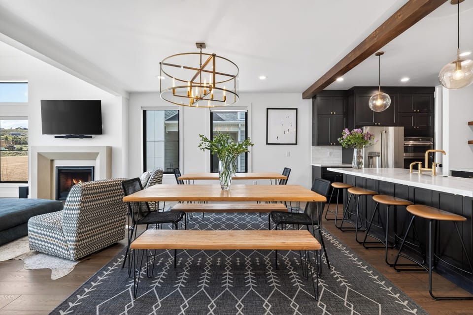 Open‑concept dining area with warm wood accents, modern lighting, and mountain views through oversized windows.